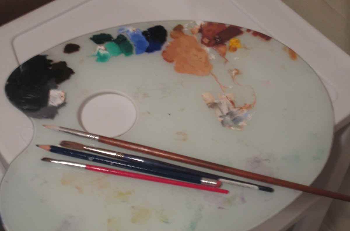 Her palette: a white oval with greens, blues, a dark heap of black and umber, flesh tones and a dab of yellow, three brushes laid across it